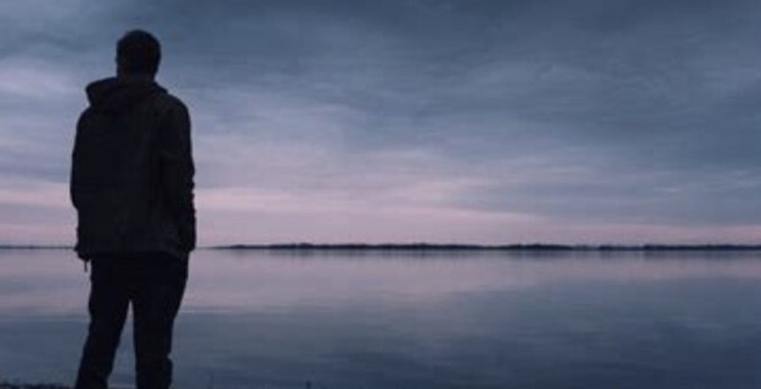 Person standing looking at lake